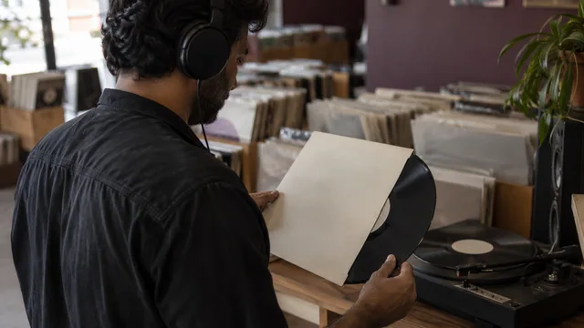 A DJ listening to a vinyl record in a small record shop